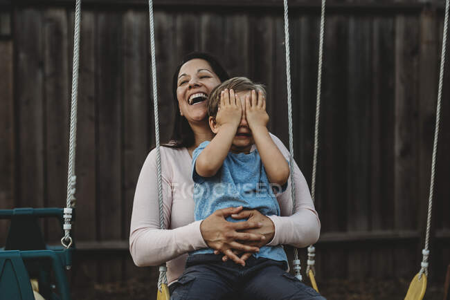 Young boy with happy mom  on swing outdoors — Fotografia de Stock