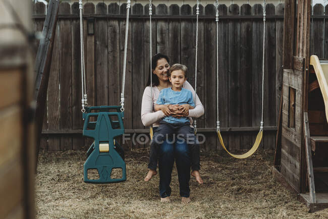 Young boy with happy mom  on swing outdoors — Stock Photo