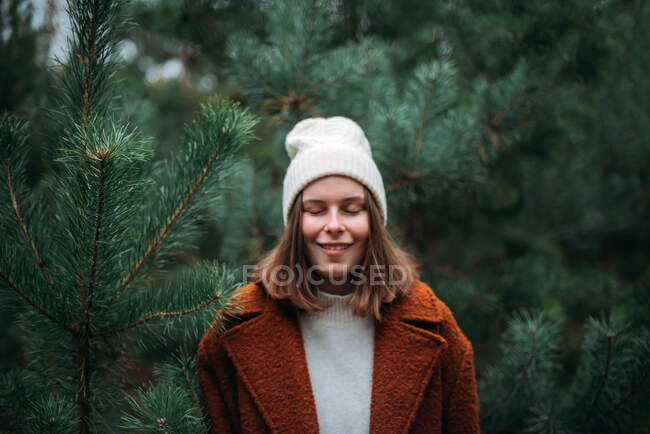 Mujer joven y bonita en ropa de abrigo de pie y relajante en el parque - foto de stock