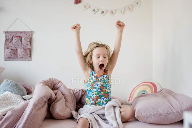 Junges Mädchen wacht morgens auf und dehnt sich in ihrem Schlafzimmer zu Hause — Stockfoto
