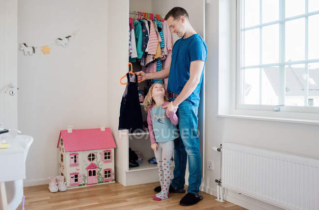 Padre aiutare la figlia a scegliere il suo vestito al mattino a casa — Foto stock