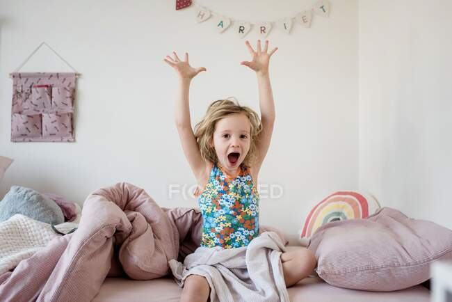Muchacha joven estirándose y bostezando en la mañana en su cama en casa - foto de stock