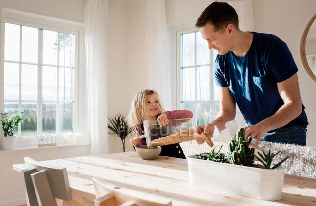 Отец помогает своей дочери готовить завтрак по утрам дома — стоковое фото