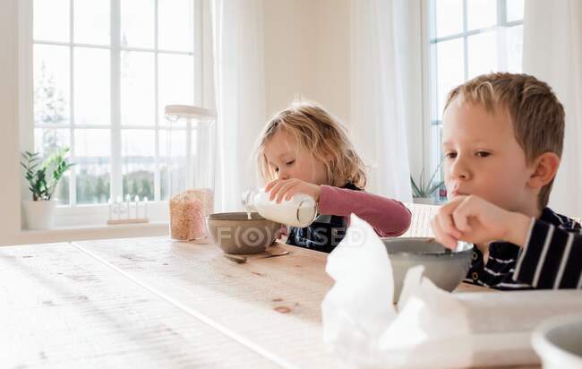 Brother and sister eating breakfast at home before school — Stock Photo