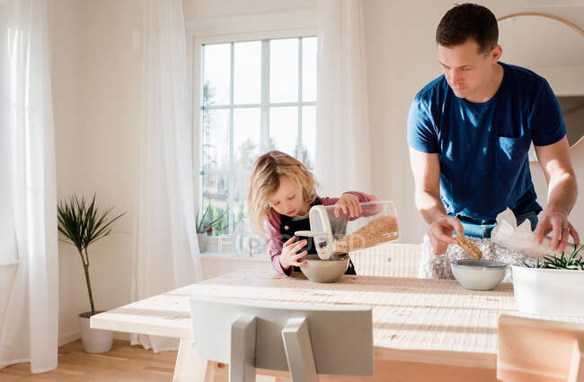 Padre ayudando a su hija a hacer el desayuno y prepararse para la escuela - foto de stock