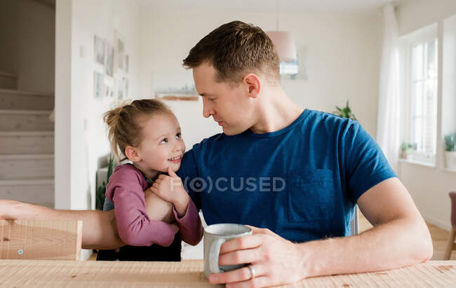 Little girl cuddling her daddy in the morning before school — Stock Photo