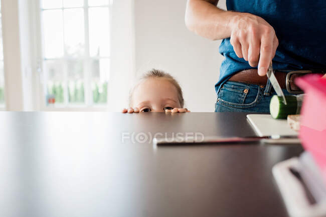 Padre fare un pranzo al sacco per la scuola mentre sua figlia guarda — Foto stock