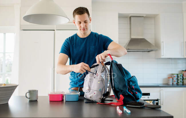 Father packing his kids school bags in the morning at home — Stock Photo