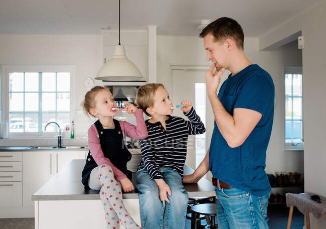 Padre insegnare ai suoi figli come lavarsi i denti prima di scuola — Foto stock