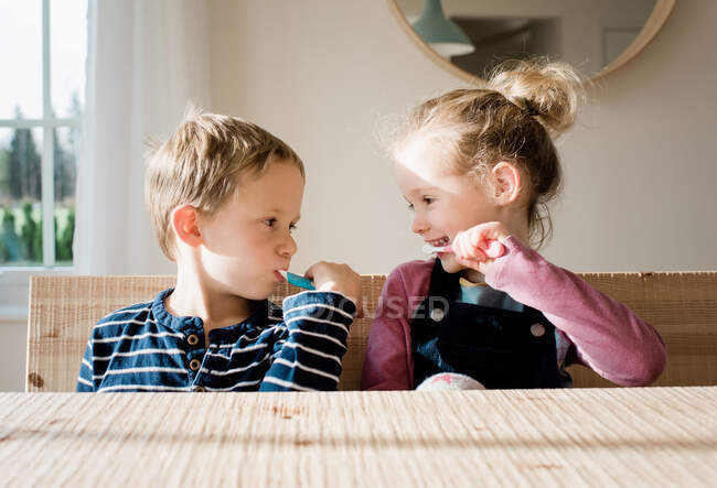 Brother and sister brushing their teeth at home before school — Stock Photo