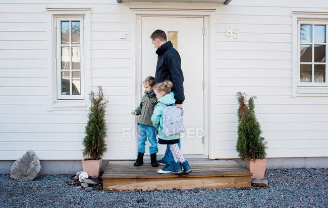 Vater bringt seine Kinder zur Schule und schließt zu Hause die Haustür ab — Stockfoto