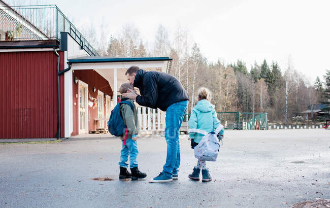 Father kissing his kids goodbye at the school gates — Stock Photo