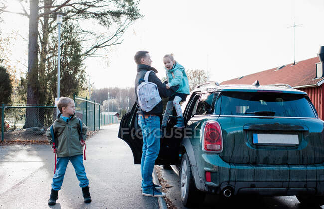 Батько кидає своїх дітей в школу вранці — стокове фото