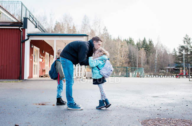 Padre dire addio ai suoi figli al cancello della scuola — Foto stock