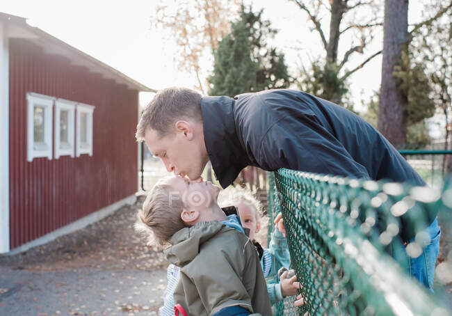 Батько цілує сина на прощання біля шкільних воріт — стокове фото