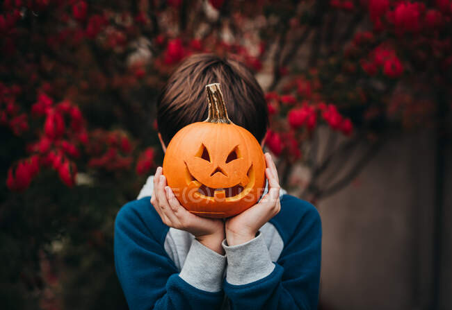 Halloween pumpkin and boy on autumn background — Stock Photo