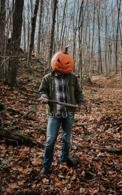 Homem usando cabeça de abóbora esculpida assustadora na floresta para o Halloween. — Fotografia de Stock