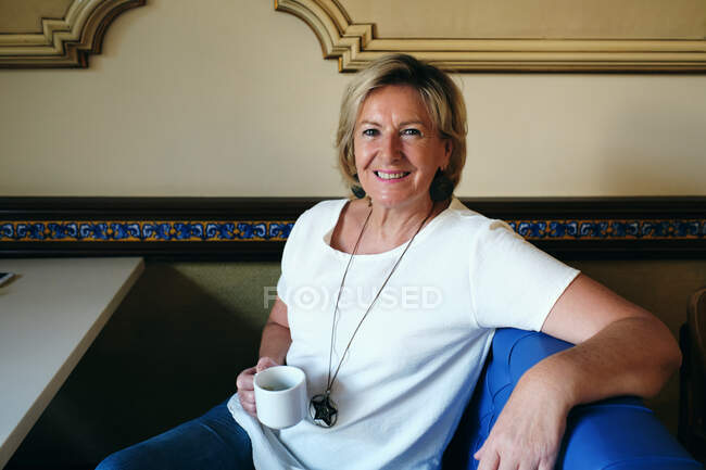 Dame trinkt Kaffee in Cafeteria lächelnd und entspannt — Stockfoto