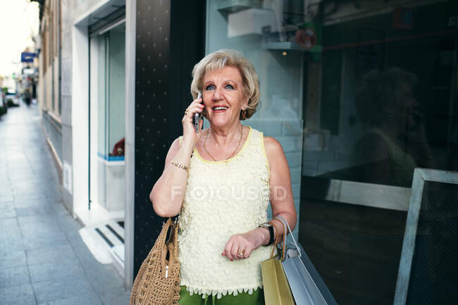 Señoras hablando por teléfono con sus bolsas de la compra - foto de stock
