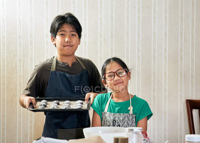 Bother and sister showing their cookie dough on the baking tray — Stock Photo