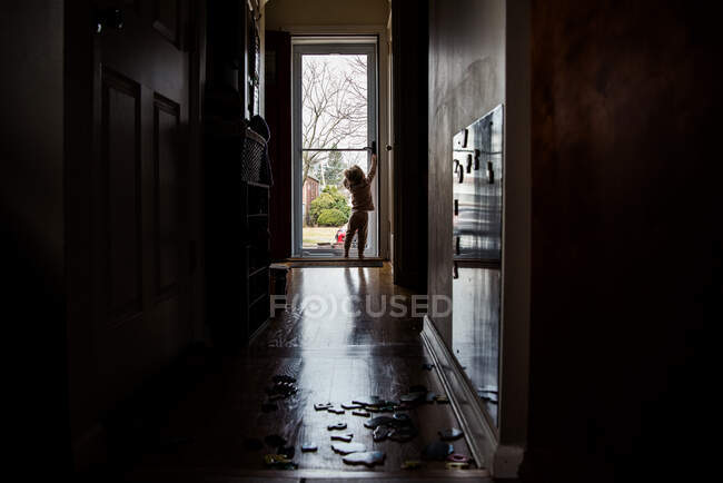 Um menino criança tenta abrir a porta da frente. — Fotografia de Stock