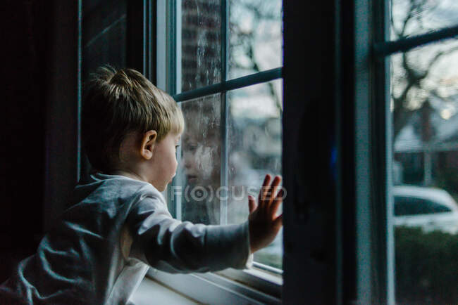 Um rapazinho olha pela janela. — Fotografia de Stock