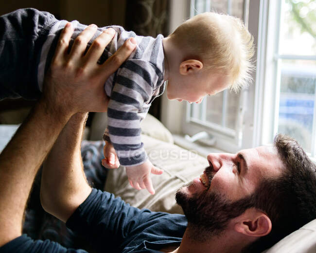 A father holds up his baby boy. — Stock Photo