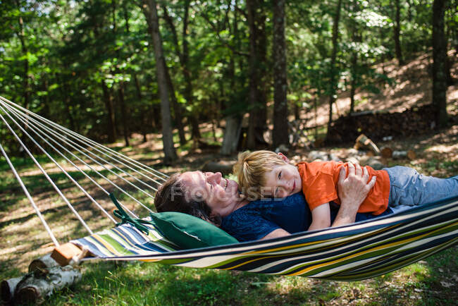 A little boy lies with his grandmother in a hammock. — Stock Photo