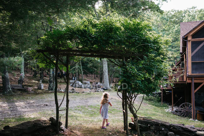 Ein kleines Mädchen spaziert unter einer Laube. — Stockfoto