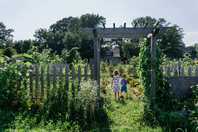 Zwei Kinder stehen unter einem Bogen in einem Garten. — Stockfoto