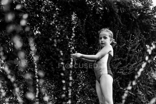 Uma menina brinca no aspersor. — Fotografia de Stock