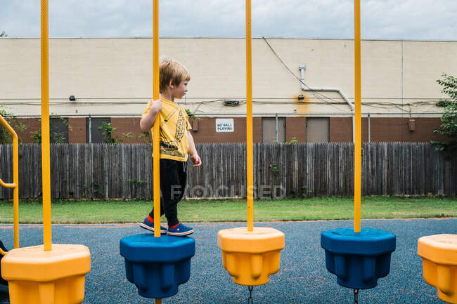 A little boy walks across a play structure. — Stock Photo