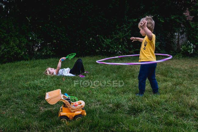 Un niño y una niña juegan con juguetes en su césped. - foto de stock