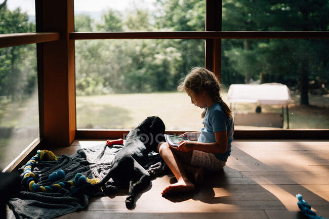 A little girl sits with her dog on a porch. — Stock Photo