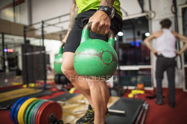 Ausgeschnittene Ansicht eines Mannes mit Kettlebells im Fitnessstudio. — Stockfoto