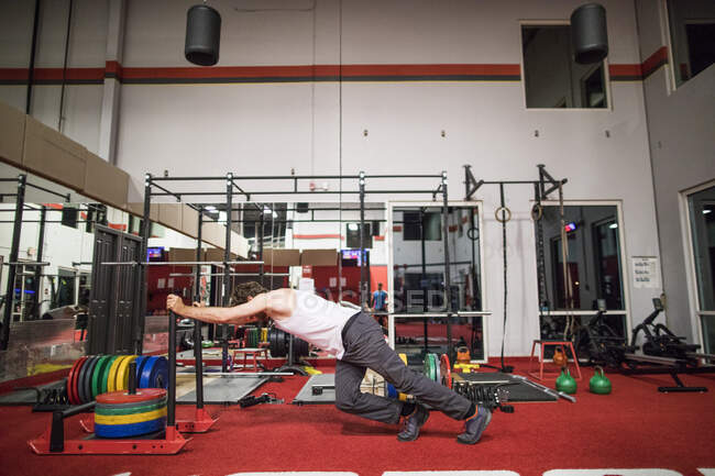 Активный человек толкает сани в фитнес-студии — стоковое фото