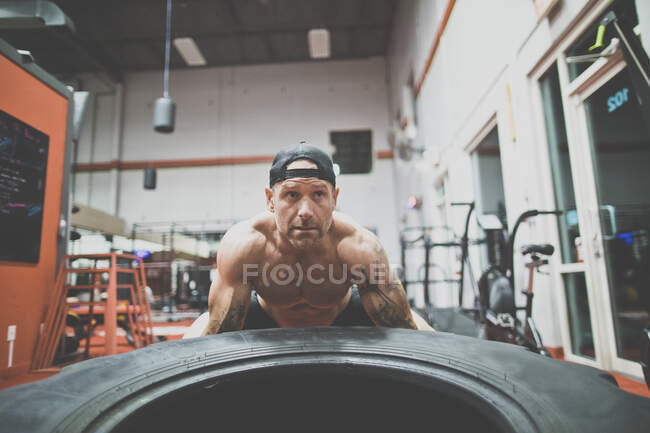 Bodybuilder lifting giant tire at the gym — Stock Photo