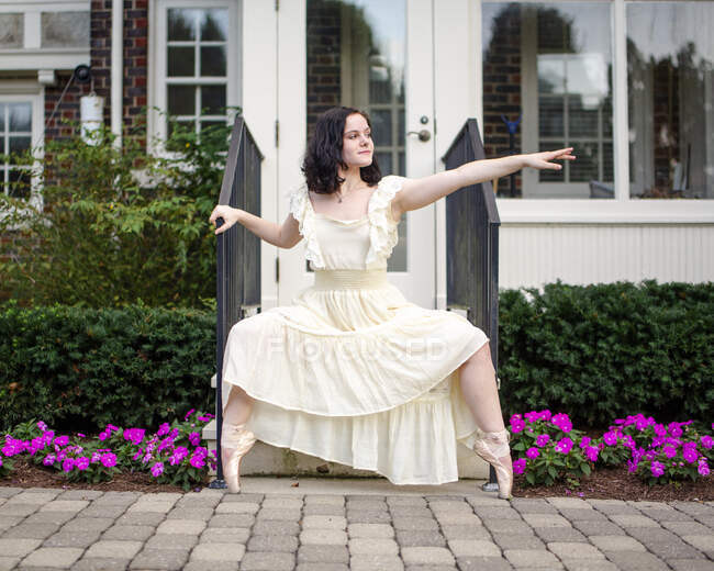 Dancer in ballet slippers standing on her toes in front of house — Stock Photo