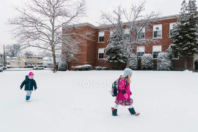 Zwei Kinder laufen im Schnee zur Schule. — Stockfoto