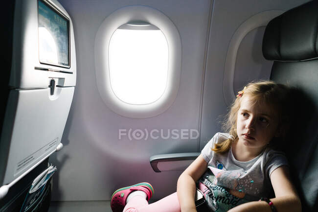 Una niña ve una película en un avión. - foto de stock