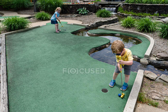 Duas crianças jogam mini golfe. — Fotografia de Stock