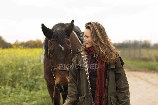 Молода жінка з конем на трасі — стокове фото