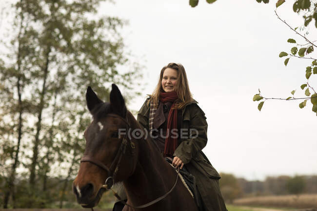 Jeune cavalière avec un cheval à l'extérieur — Photo de stock