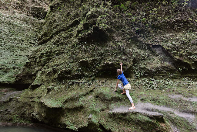 Tween menina escalando no penhasco verde — Fotografia de Stock