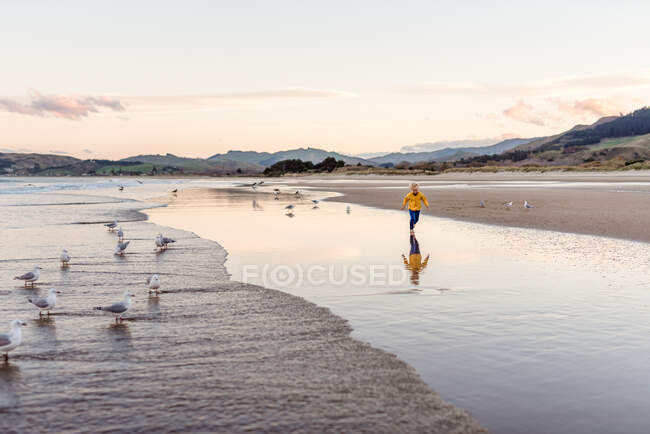 Kleiner Junge läuft mit Reflexion am Strand — Stockfoto