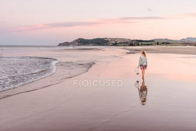 Nettes Mädchen, das bei Sonnenuntergang am Strand spaziert — Stockfoto
