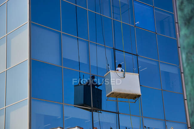 Ouvrier nettoyant les fenêtres dans un bâtiment moderne en verre, Pampelune Espagne — Photo de stock