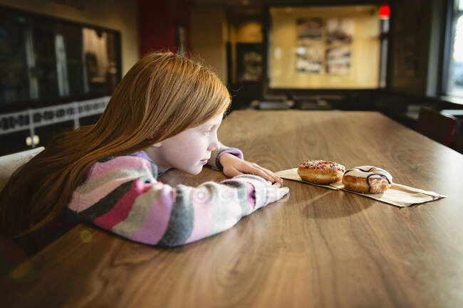 Petite fille manger des biscuits dans la cuisine — Photo de stock