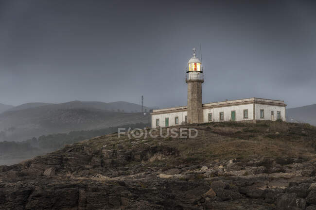 Faro y una torre en la costa y el mar - foto de stock