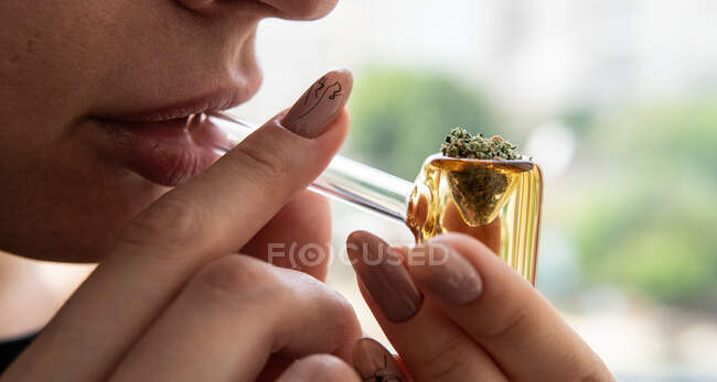 Fumar cannabis por tubo amarillo de vidrio primer plano. Fumar cultura - foto de stock